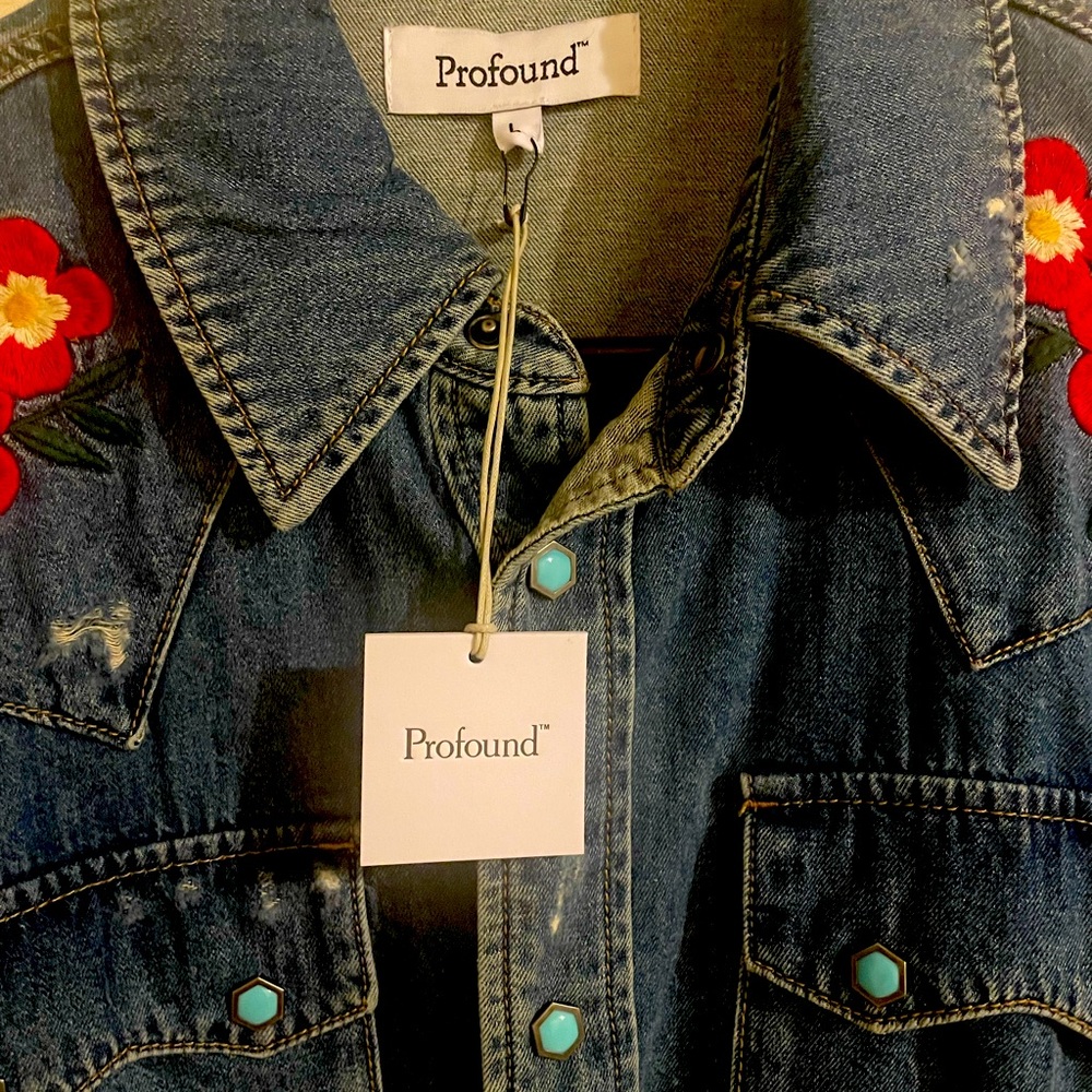 A distressed denim long sleeve shirt with floral stitching and turquoise buttons